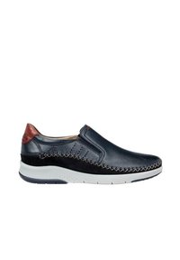 Zapato deslizante de cuero azul marino con un diseño cosido y acentos en marrón, que presenta una suela blanca texturizada y detalles perforados a lo largo de los lados.