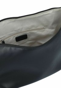 Interieur van een zwarte leren tas met een gladde textuur, voorzien van een ritszak en een lichte voering. Minimale branding zichtbaar.