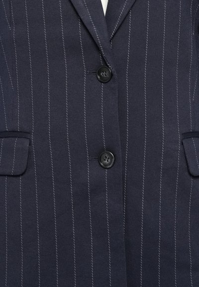 Mørk marineblå blazer med striper, to svarte knapper og klaffelommer, som viser frontmidten og kragen.
