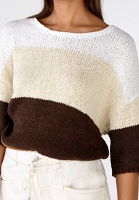 Suéter de punto con tres bloques de color: parte superior blanca, parte media beige y parte inferior marrón. Escote amplio y mangas cortas. Textura suave.