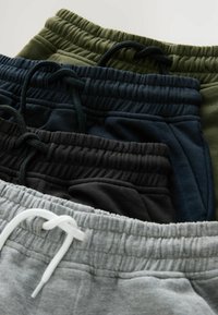 Čtyři páry tepláků v šedé, černé, námořnické modři a olivově zelené, s elastickým pasem na šňůrky a hladkým bavlněným povrchem.