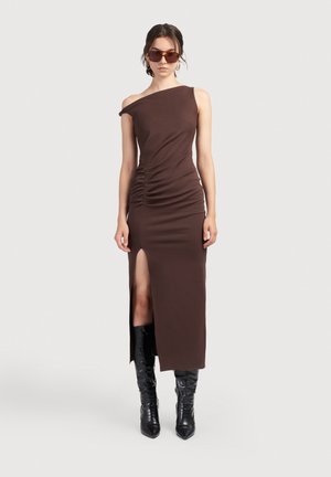 Ruda su viena petneša su šoniniu raukiniu ir aukštu šlaunies pjūviu, pagaminta iš minkštos medžiagos. Derinama su juodais iki kelių auliniais batais ir saulės akinių.