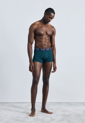 Herre grønne boxer shorts med elastisk mørkeblå talje, der fremhæver "PUMA"-branding, glat stof, tætsiddende design og kort benlængde.