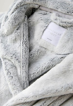 Gaiši pelēks, mīksts mākslīgā kažokādas halāts ar strukturētu virsmu un birku ar uzrakstu "NIGHTWEAR by NEXT." Iekļauj kapuci un atvērtu priekšpusi.