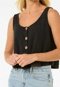 Schwarzes kurz geschnittenes Oberteil aus strukturiertem Stoff mit Rundhalsausschnitt und vier Holzknöpfen vorne, kombiniert mit hellblauen Jeansshorts.