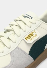 PUMA tenisice s bijelim gornjim dijelom od kože, zelenim i sivim detaljima od brušene kože, ravnim vezicama i zlatnom oznakom s logotipom na kojoj piše "PUMA PALERMO".