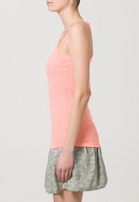 Licht koraalkleurig mouwloos tanktop met een ronde halslijn, gecombineerd met een gestreepte rok met een lichtgrijs en donkergroen ontwerp.