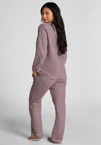 Rood-wit geruite pyjamaset gemaakt van zachte katoen, met lange mouwen en broeken met zakken, weergegeven vanuit de achterkant.