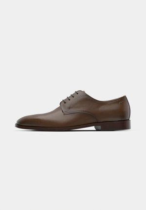 Brown leather dress shoe with a smooth finish, sleek rounded toe, and five eyelets for lacing. Flat heel and subtle branding on the side.