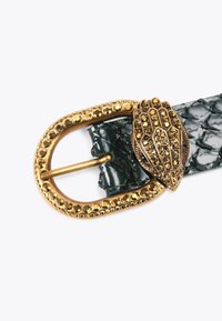 Zielony pasek w krokodyle wzór z teksturowaną klamrą w złotym odcieniu, która przedstawia rękę i ma dekoracyjne cyrkonie wokół krawędzi.