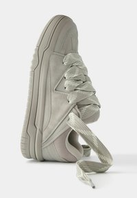 Jasnoszare trampki z mieszanką zamszu i siateczki, grube, teksturowane sznurowadła, podwyższona gumowa podeszwa oraz elegancki, nowoczesny design.