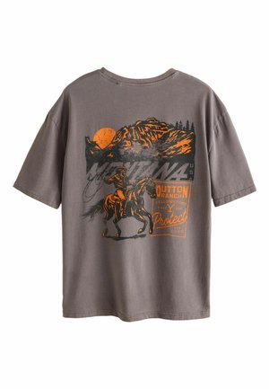Grå t-shirt med grafik af en cowboy på en hest, bjerge, sol, træer og tekst, der refererer til Dutton Ranch og Yellowstone.