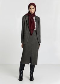 Blazer grigio scuro su misura sopra una maglia con fantasia, abbinato a una gonna midi grigia coordinata con una spacco frontale, completato da un hijab bordeaux.