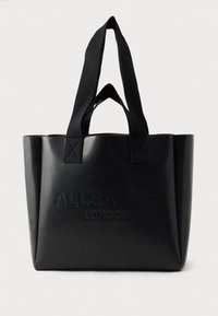 Bolsa tote preta feita de material brilhante, com forma retangular, alças suaves, logotipo em relevo e interior em tom contrastante de bege.