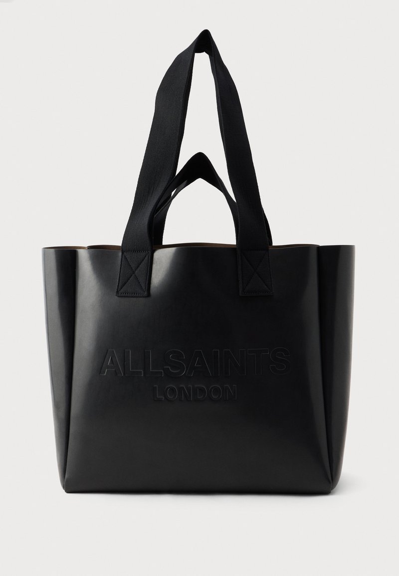 Bolsa tote preta feita de material brilhante, com forma retangular, alças suaves, logotipo em relevo e interior em tom contrastante de bege.