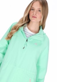 Mentazöld széldzseki kapucnival, cipzáras záródással, húzózsinóros állítással és egy kis esernyő logóval a mellrészen.