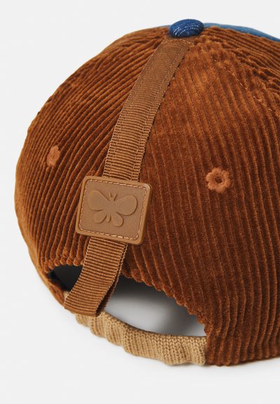 Hnedý zamatový klobúk s modrým gombíkom na vrchu, béžovým interiérom, koženou etiketou s motýľovým logom a svetlohnedým nastaviteľným popruhom na zadnej strane.