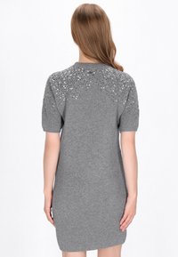 Rochie tricotată gri, cu mâneci scurte și decolteu rotund, embellisată cu paiete pe umeri. Textură moale, design ajustat.