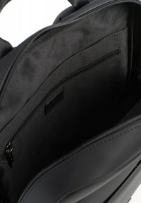 Zwarte tasinterieur met een zachte textuur, voorzien van een met rits afsluitbaar vak en een elegante voering. Het organisatiepaneel heeft een gladde afwerking en minimale details.