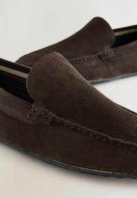 Barna suede loafer, texturált felülettel, varrott részletekkel és sima fekete gumitalppal. Egyszerű dizájn, látható fémrészletek nélkül.