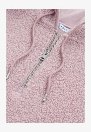 Ružičasti flis pulover s teksturiranom površinom, zatvaranjem na pola sa zipom i aluminijskim patentnim zatvaračem. Ima kengursku džep i kapuljaču.