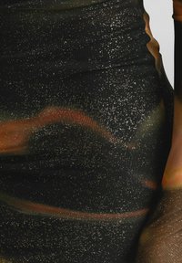 Svart klänning i tyg med glittrande textur med guldfärgade fläckar och abstrakta mönster i orange och röda nyanser; figurnära design med rynkdetaljer.