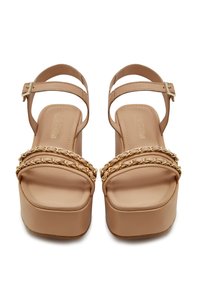 Beige platform sandalen met gouden kettingdetails, een open teen, verstelbare enkelbandjes en een zachte faux leren textuur.