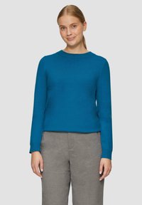 Teal coltrui met lange mouwen, gemaakt van een zachte stof, gecombineerd met grijze tailored broek. Eenvoudig, aansluitend ontwerp.
