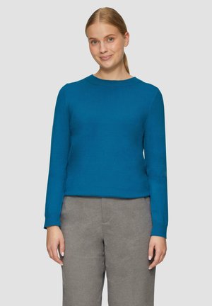 Pull-over en teal à col rond avec des manches longues, fabriqué à partir d'un matériau doux, associé à un pantalon gris taillé. Design simple et ajusté.