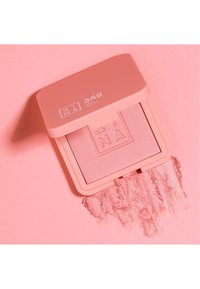 Blush compacto en una suave caja rosa, que muestra un polvo rosa suave con un ligero brillo. Presenta un logo en relieve y polvo disperso.