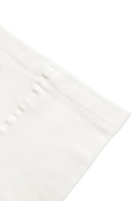 Leggings de algodón blanco con una cinturilla suave y elástica. Textura lisa y forma ajustada con detalles en las costuras y acentos de botones a lo largo del lado.