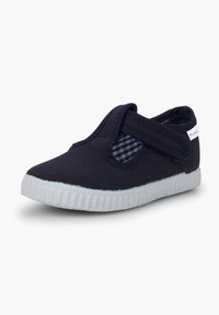 Zapatillas de lona sin cordones en azul marino con una correa de velcro, suela de goma blanca y forro de cuadros. Diseño sencillo con tela texturizada.