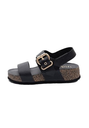 Czarna sandałka z teksturowanej skóry z dwoma paskami, złotą klamrą, korkową platformą oraz regulowanym paskiem na piętę, widziana z boku na białym tle.