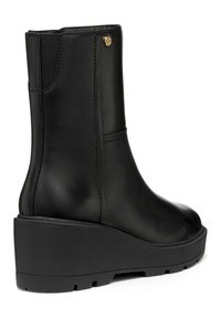 Bottines en cuir noir avec une semelle compensée, des panneaux latéraux élastiques et une touche d'or. Présente une texture lisse et une construction robuste.