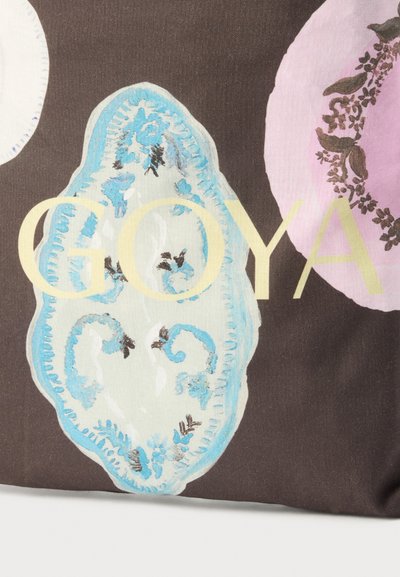 Καφέ ύφασμα με μεγάλα μπλε και ροζ αφηρημένα λουλουδένια σχήματα και τη λέξη "GOYA" σε ανοιχτό κίτρινο κείμενο στο κέντρο.