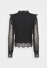 Blouse en dentelle noire à manches longues avec manches transparentes à pois, bordure à volants, col montant et détail d'ourlet festonné.