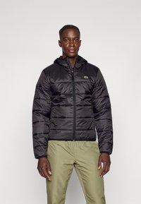 Black padded jacket with a hood, featuring horizontal quilting and a zip closure. Includes a small green logo on the left chest.