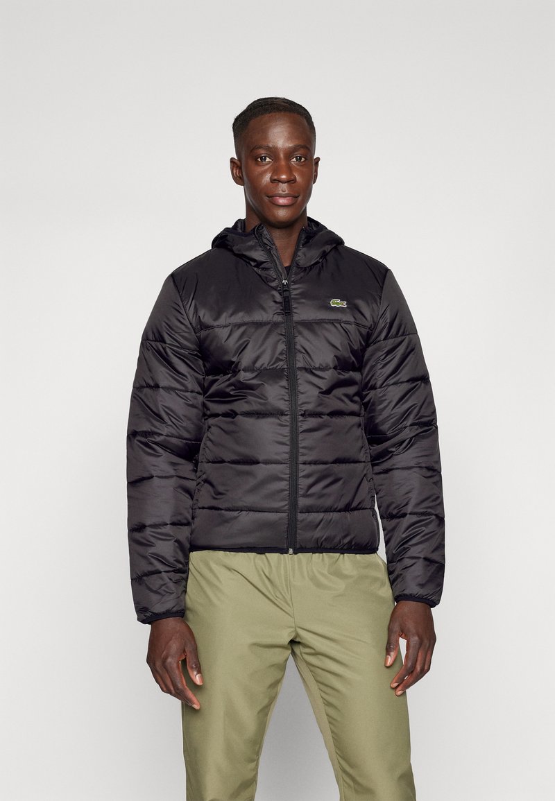Black padded jacket with a hood, featuring horizontal quilting and a zip closure. Includes a small green logo on the left chest.