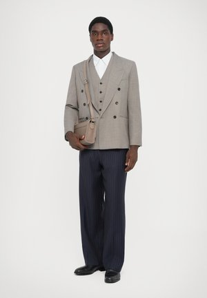 Gray double-breasted blazer over a white shirt, paired with pinstriped navy trousers, and a small beige shoulder bag. Black shoes included.