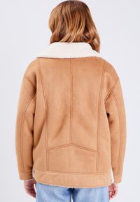 Giacca in finta suede beige con colletto in shearling crema, vestibilità oversized e cuciture a contrasto. Presenta una texture liscia e tasche laterali.