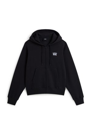 Giovane che indossa una felpa nera Vans con cappuccio e zip, cappellino grigio, mani in tasca, su sfondo bianco semplice.