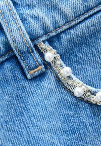 Tussă denim de culoare albastru deschis cu cusături vizibile. Accente decorative din argint, cu pietre strălucitoare și perle albe de-a lungul marginii.