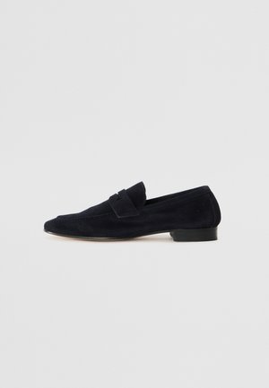 Marineblaue Wildleder-Loafer mit niedrigem Absatz, ausgestattet mit einem Vorderbanddetail und genähten Akzenten, glatter Textur und klassischer Form.