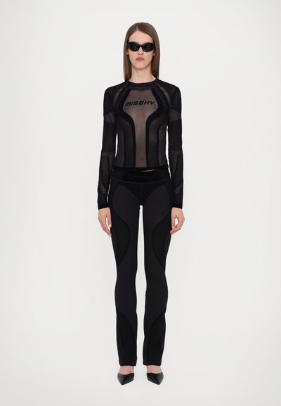 Black mesh long-sleeve top with vertical stripes and logo, paired with black fitted leggings featuring curved designs and textured accents.