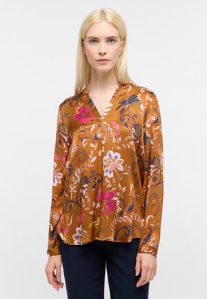 Brun blomstret bluse med lange ærmer, V-hals, der har pink, blå og lilla blomstermønstre på et silkeagtigt stof. Rundet kantdetalje.