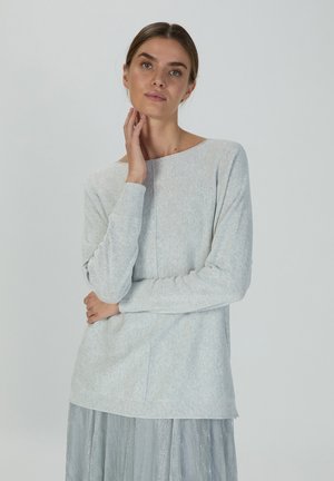 Helles graues Langarmshirt mit einem Bootsausschnitt und gerippten Bündchen, das eine weiche Textur und eine lockere Passform aufweist, kombiniert mit einem metallischen Rock.