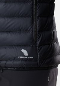 Section de veste matelassée noire avec poche zippée verticale, logo plume blanche, texte "PREMIUM DOWN" et ourlet de marque "SWEDEMOUNT."