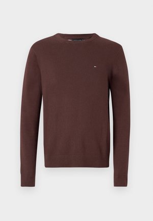 Rudas megztinis su ilgomis rankovėmis, apvaliu iškirpimu ir maža logotipu ant krūtinės. Lygus paviršius su grafitinėmis detalėmis ant rankogalių ir apatinės dalies.