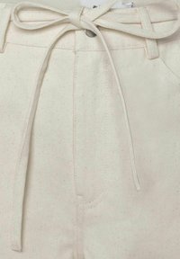 Weiße Baumwollhosen mit strukturiertem Finish, ausgestattet mit einem vorderen Band, genähten Taschen und einem subtilen gesprenkelten Muster.