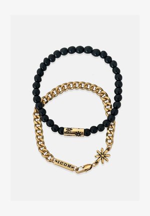 Čierny korálkový náramok v kombinácii so zlatým náramkom. Obsahuje zlatý kvetinový akcent a detail zapínania "ICON". Rôzne textúry a kontrastné materiály.